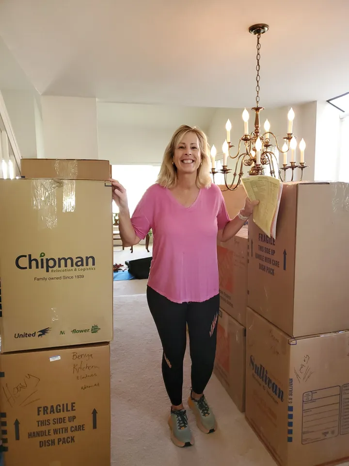 Woman smiling among stacked moving boxes.